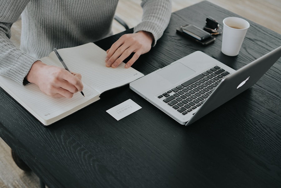 Writing notes at a desk beside a laptop